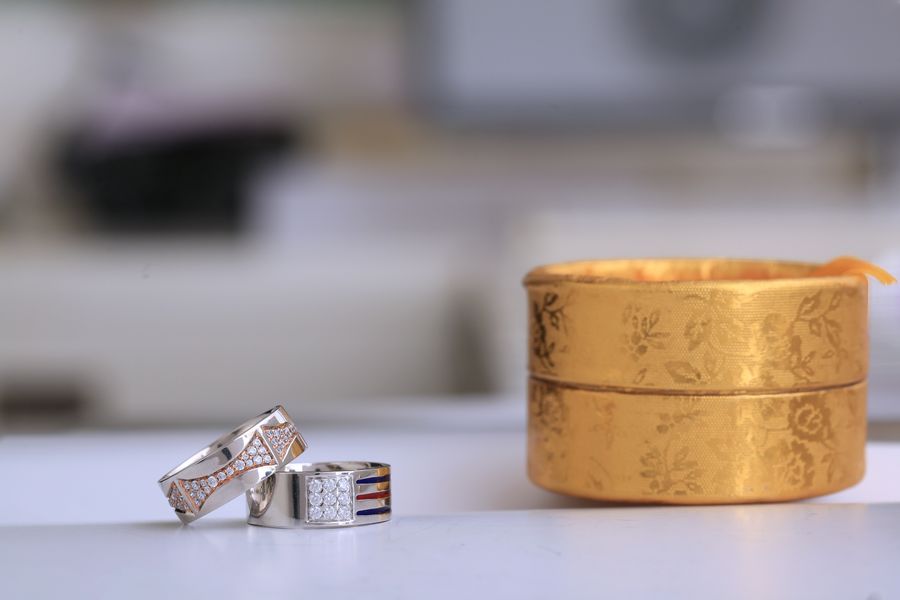 Silver wedding rings with diamonds next to a gold box