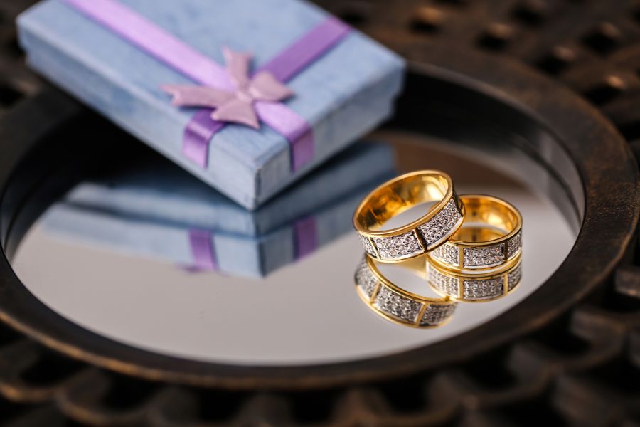 Gold wedding rings reflecting next to a blue gift box