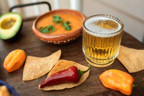 Free Delicious Mexican food setup with beer, salsa, and peppers for a culinary delight. Stock Photo