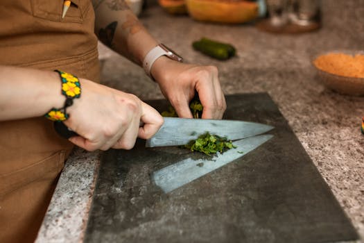 A person chopping fresh herbs with a knife on a kitchen countertop. Perfect for cooking and culinary themes.