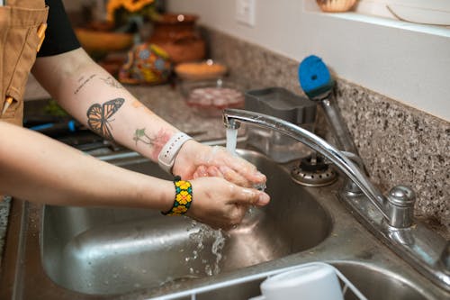 Personne En Bracelet Jaune Et Noir Se Laver Les Mains Sur L'évier