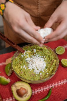 Close-up of fresh homemade guacamole with feta cheese and lime slices, perfect for Mexican cuisine lovers.