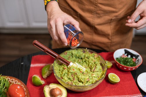 Free Crop faceless person adding cut tomatoes in bowl with guacamole Stock Photo