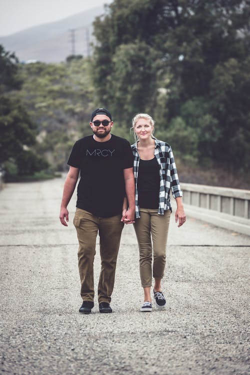 Free A Couple Walking on Concrete Bridge Hand in Hand Stock Photo