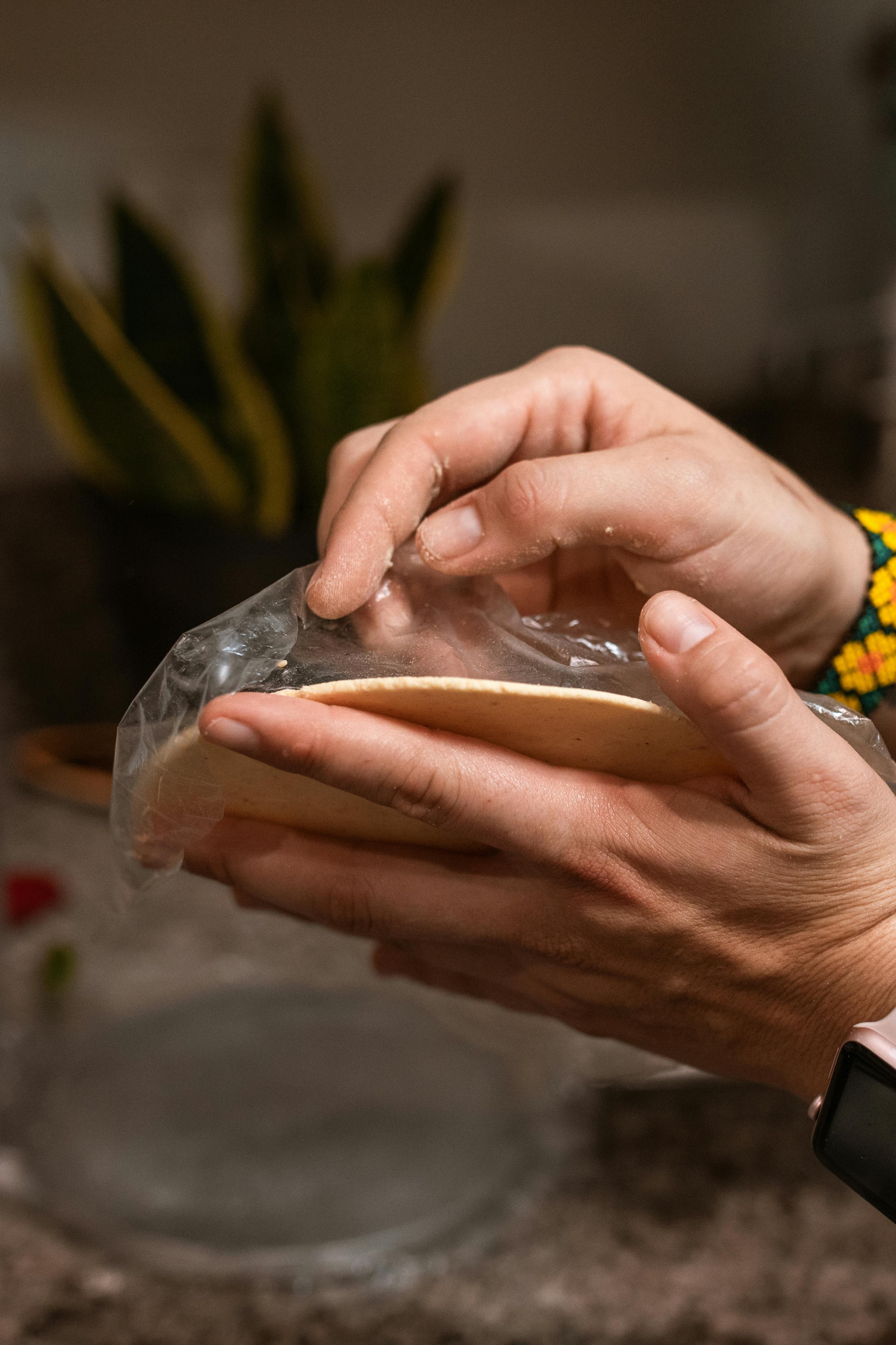 Hands preparing a tortilla in a kitchen setting, evoking a cozy cooking atmosphere.