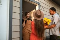 A Woman Standing on a Doorway in Front of People Bringing Flowers
