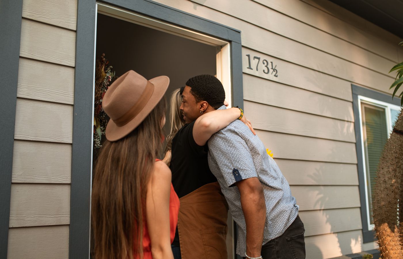 Three adults warmly embrace at a doorway, exuding friendship and connection.