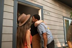 Three adults warmly embrace at a doorway, exuding friendship and connection.