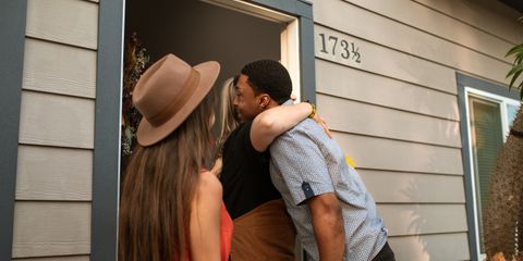 Three adults warmly embrace at a doorway, exuding friendship and connection.