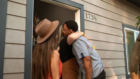 Three adults warmly embrace at a doorway, exuding friendship and connection.