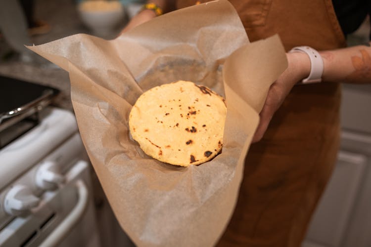 A Person Holding A Round Bread On A Wax Paper