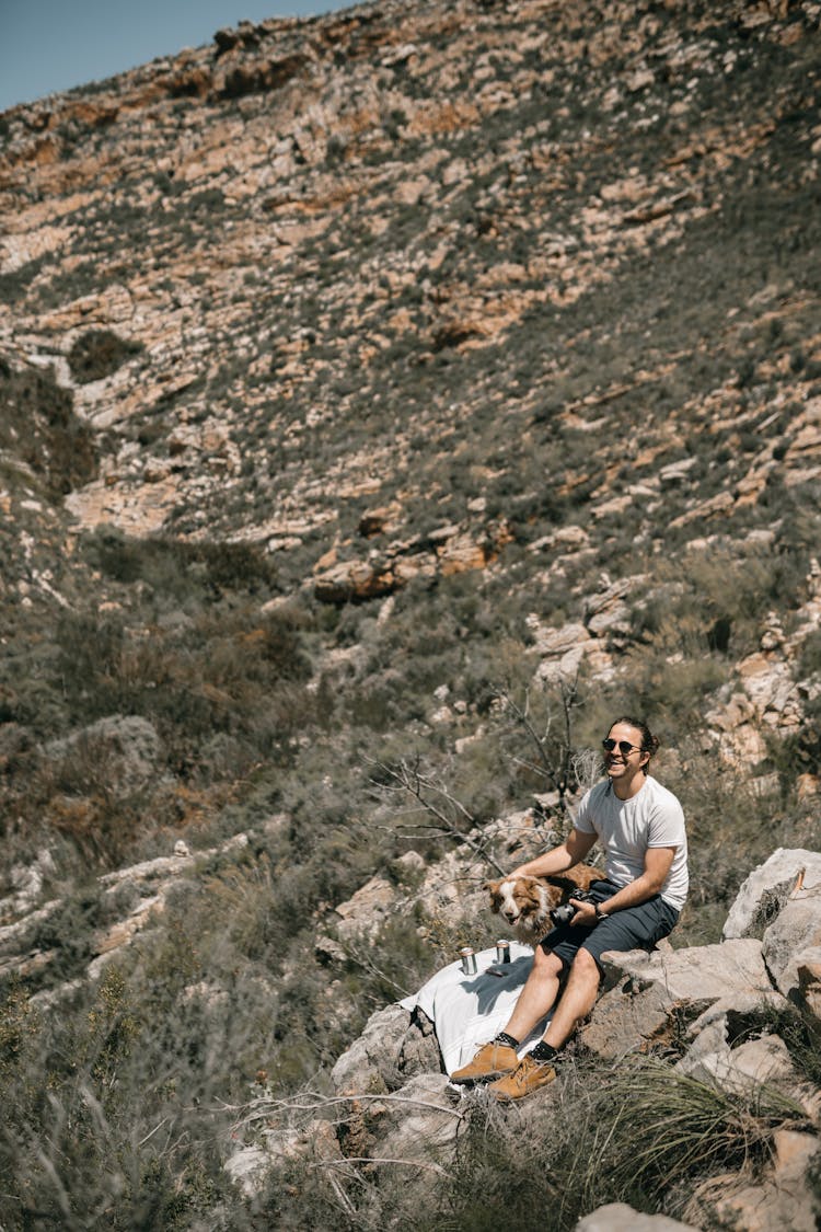 Man Hiking With Dog Sitting On Rock