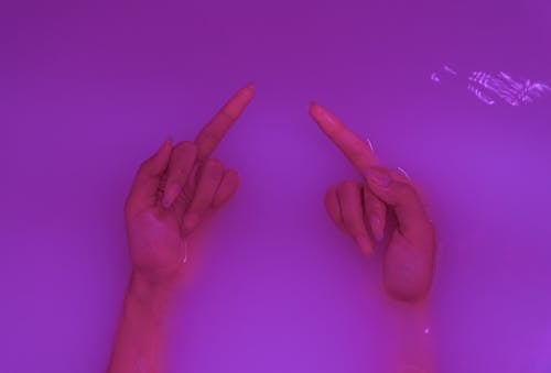Free Top view of crop anonymous rude female demonstrating middle fingers in aqua with neon light Stock Photo