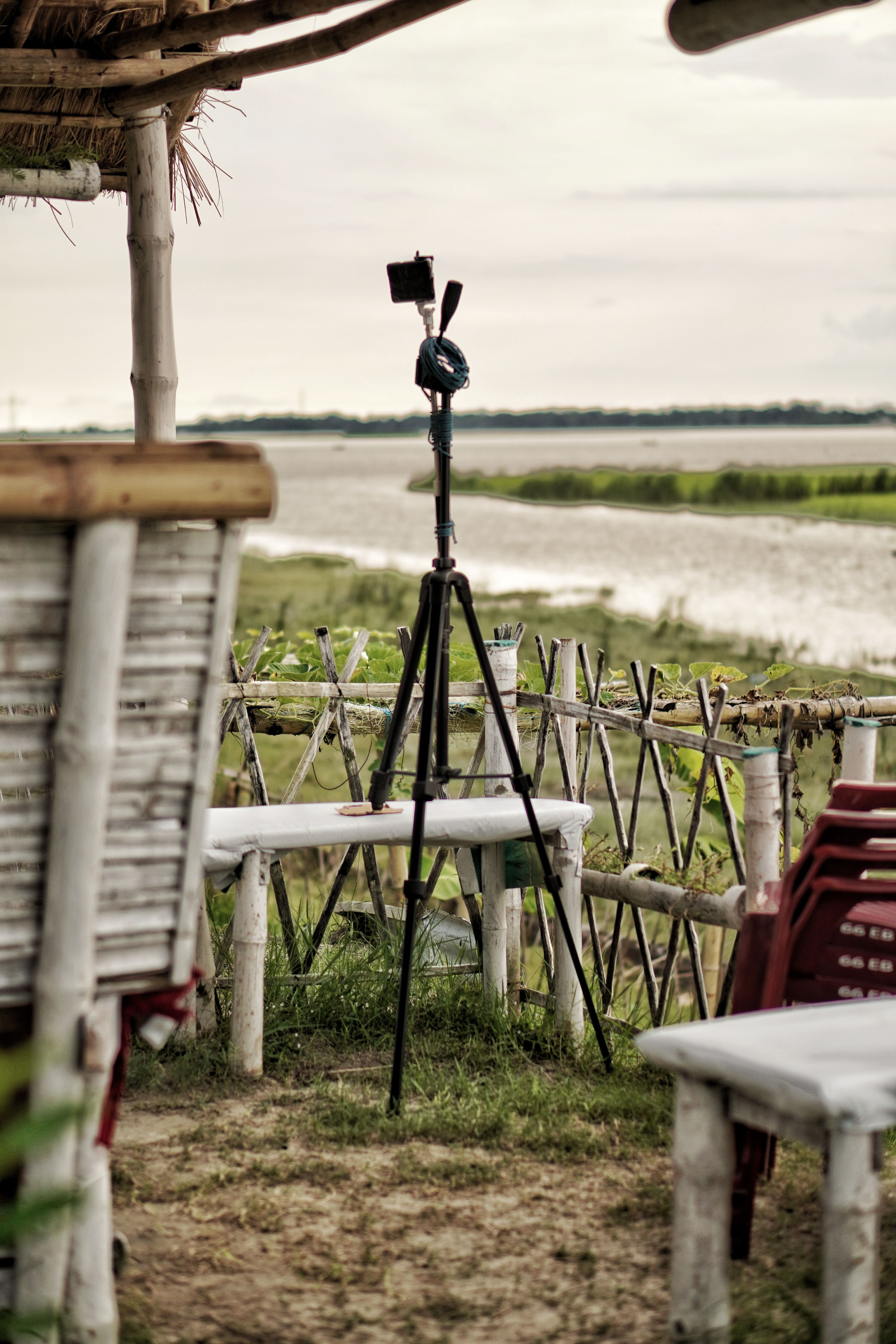 Explore a serene outdoor setting with a tripod and rustic furniture by the riverside.