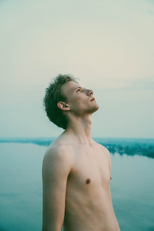 Dreamy man with naked torso against lake
