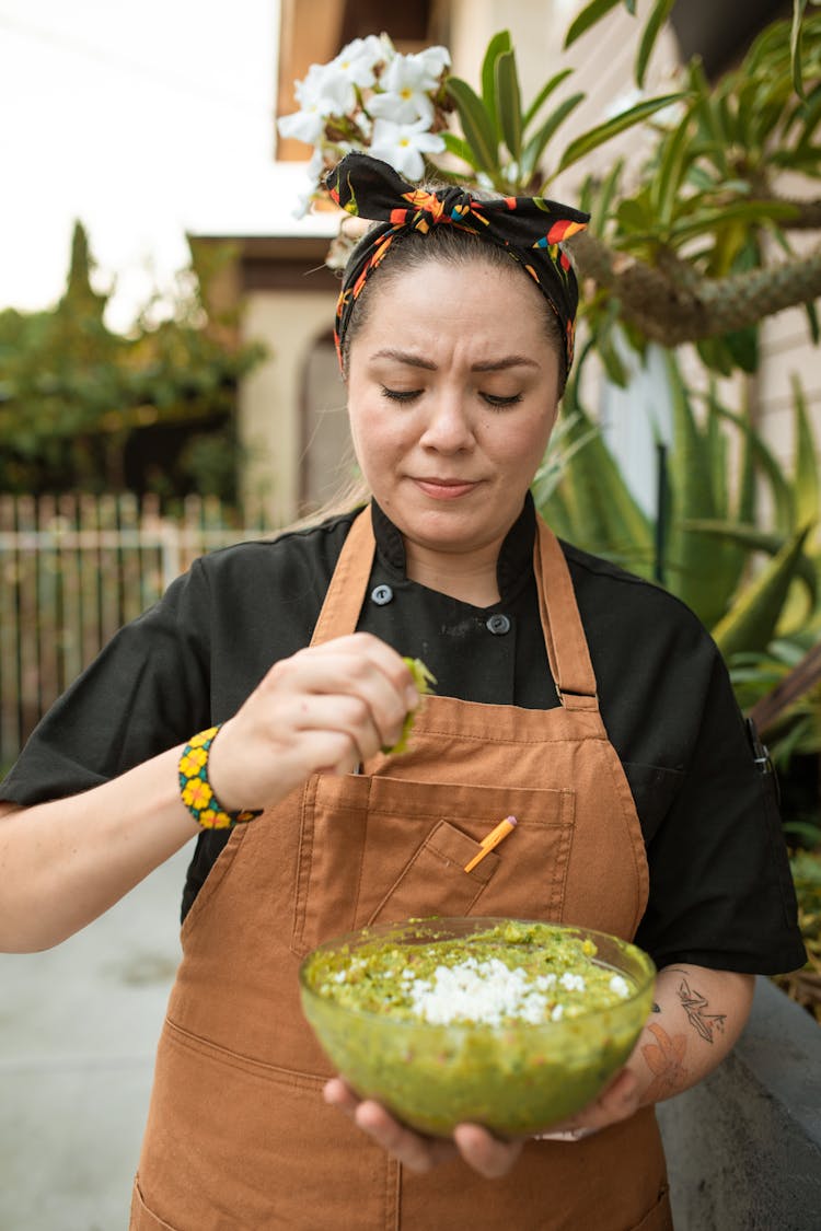 A Female Chef Squeezing A Lime Into A Bowl Of Guacamole