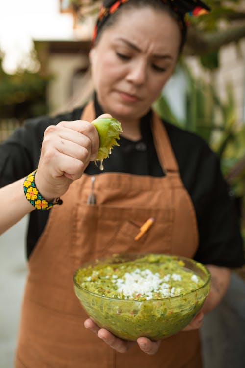 A Female Chef Squeezing a Lime into a Bowl of Guacamole