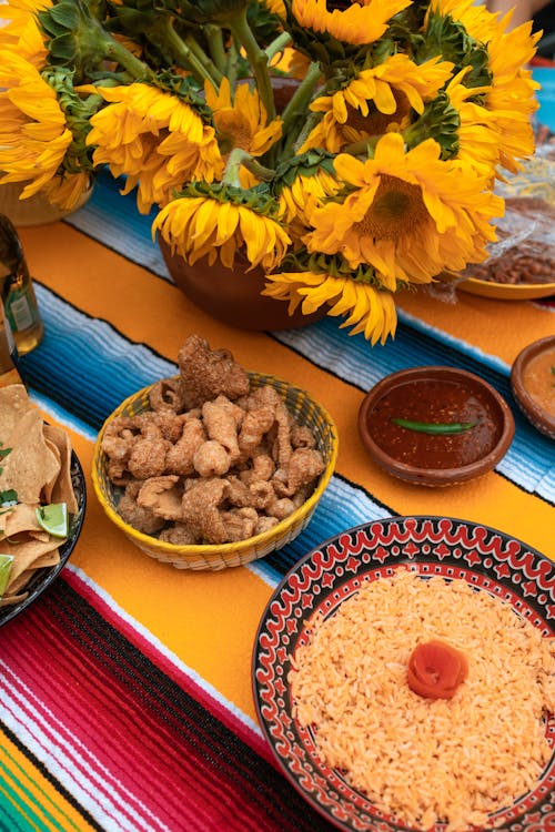 Free A Delicious Bowls of Fried Pork Rinds and Fried Rice Near a Vase of Sunflowers Stock Photo