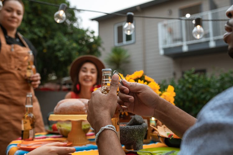 A Person Holding A Bottle Of Beer And A Bottle Opener