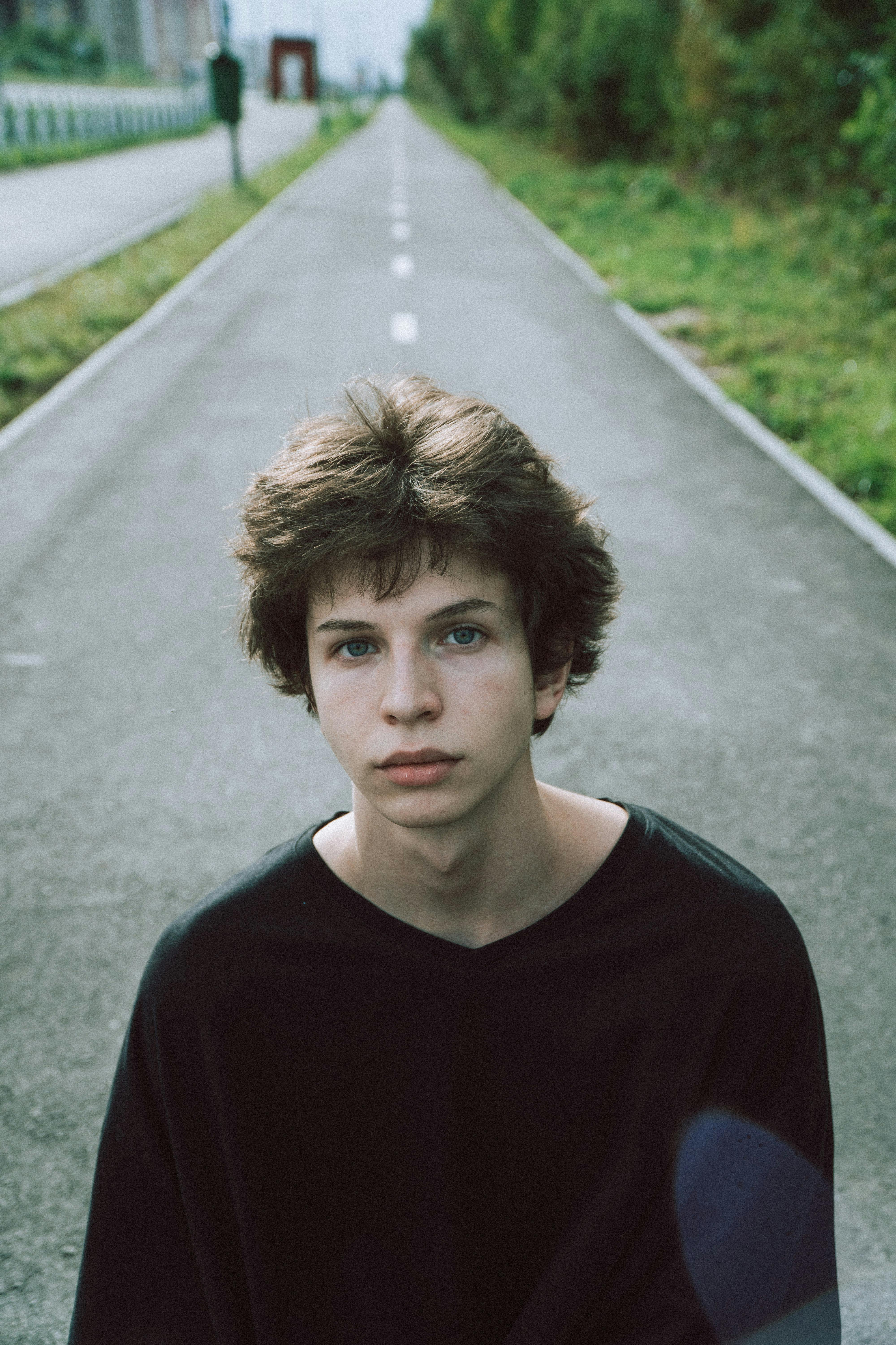 teen on straight road between grass in summer