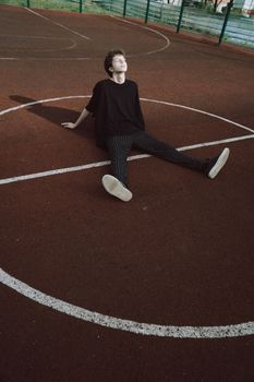 白天，一位梦幻般的男性青少年闭着眼睛，双手靠在游乐场上