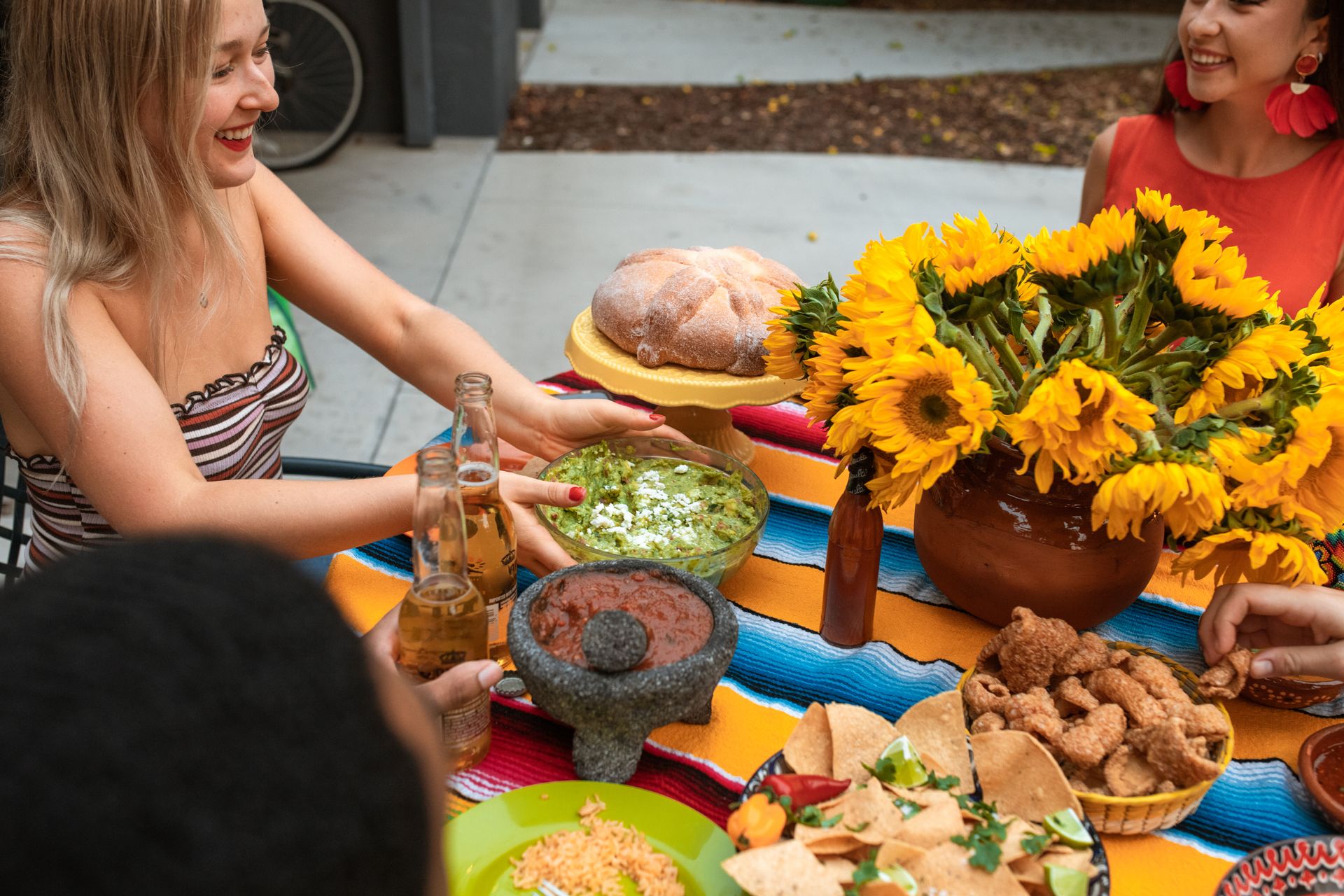Friends enjoy a colorful outdoor meal with Mexican food, bright sunflowers, and lively conversation.