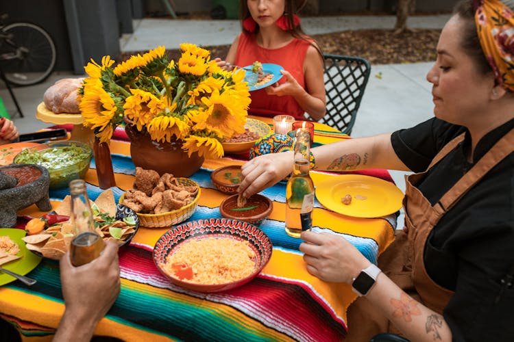 Women Sitting At A Table With Food 