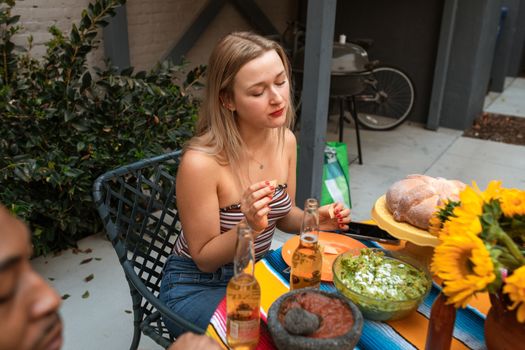 一位女士在露台上品尝墨西哥美食和饮料，周围环绕着鲜艳的色彩和新鲜的食材