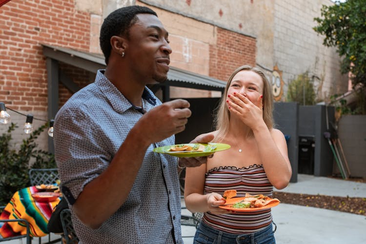 Man And Woman Eating Mexican Food While Standing