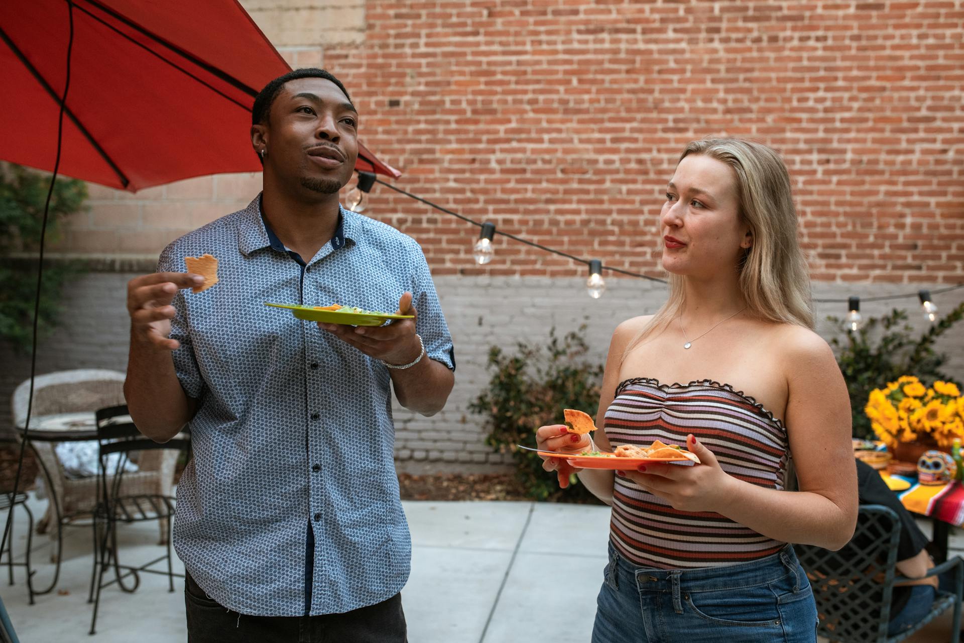 Two people enjoying Mexican food at a casual outdoor gathering.