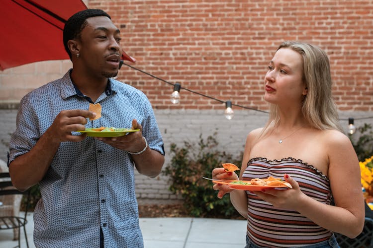 Man And Woman Eating Food While Standing