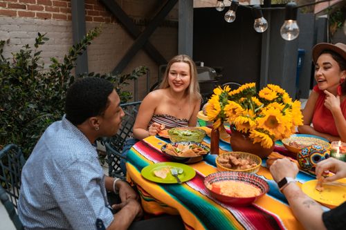 Free Friends enjoying a lively outdoor meal with Mexican food and bright decorations. Stock Photo