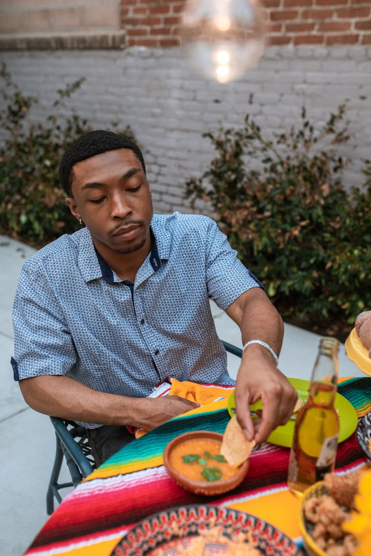 Man Dipping The Nachos In The Orange Sauce 