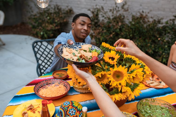 Man Passing The Ceramic Bowl With Nachos 