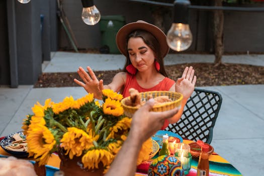A woman at an outdoor table with vibrant sunflowers and Mexican food, expressing reluctance.
