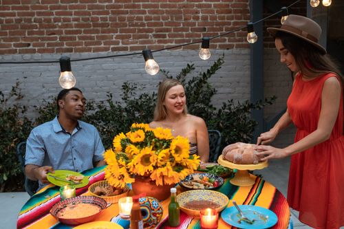 Free A group of friends enjoying a vibrant outdoor dinner party with sunflowers and festive decor. Stock Photo