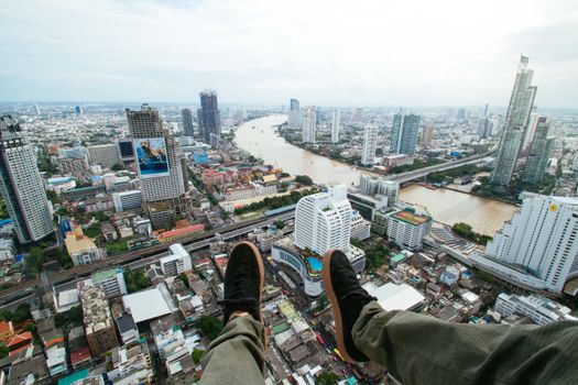 从空中俯瞰曼谷惊心动魄的城市景观，河流在前，鞋子置于前景