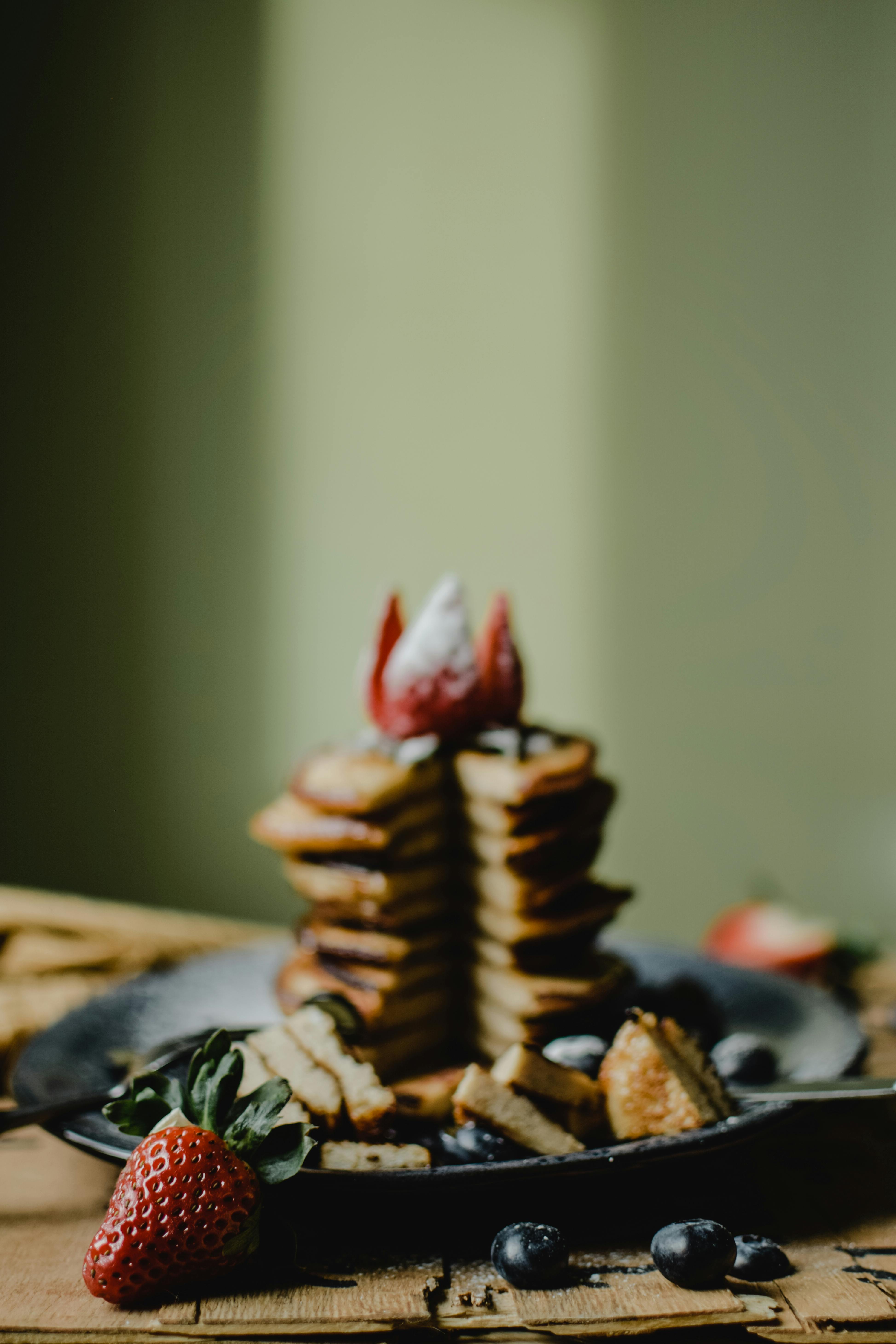 Mouthwatering stack of pancakes topped with strawberries and blueberries, perfect for breakfast.