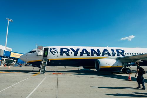 Free Ryanair airplane parked at airport, with clear blue sky and boarding ladder visible. Stock Photo