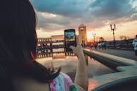 一名妇女拍下了一张城市日落倒映在池塘中的照片，景象引人注目