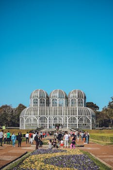在蓝天下，巴西植物园充满活力的场景中，游客们穿梭于标志性的温室之间