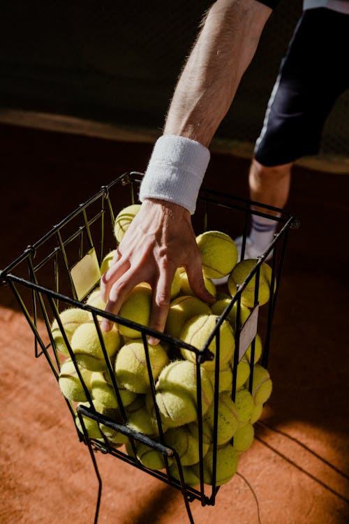 Free A Person Holding Green Tennis Balls Stock Photo