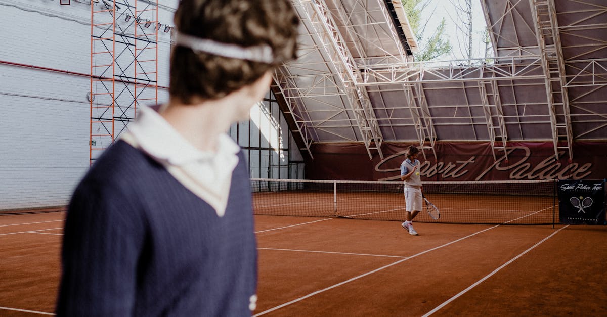 Tennis players on an indoor clay court during a competitive match.