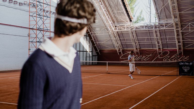 Tennis players on an indoor clay court during a competitive match.