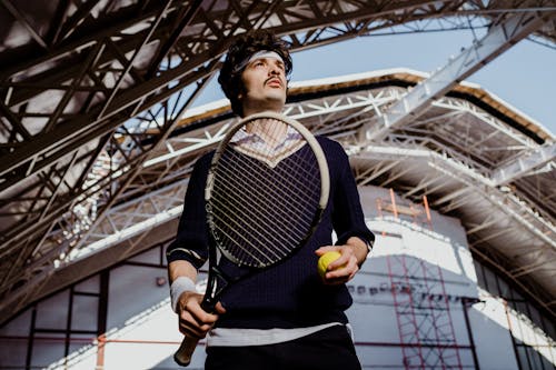 Man in Black Sweater Holding Yellow and Black Tennis Racket