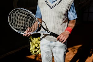 Person in Blue and White Shirt and White Pants Holding Black and White Tennis Racket