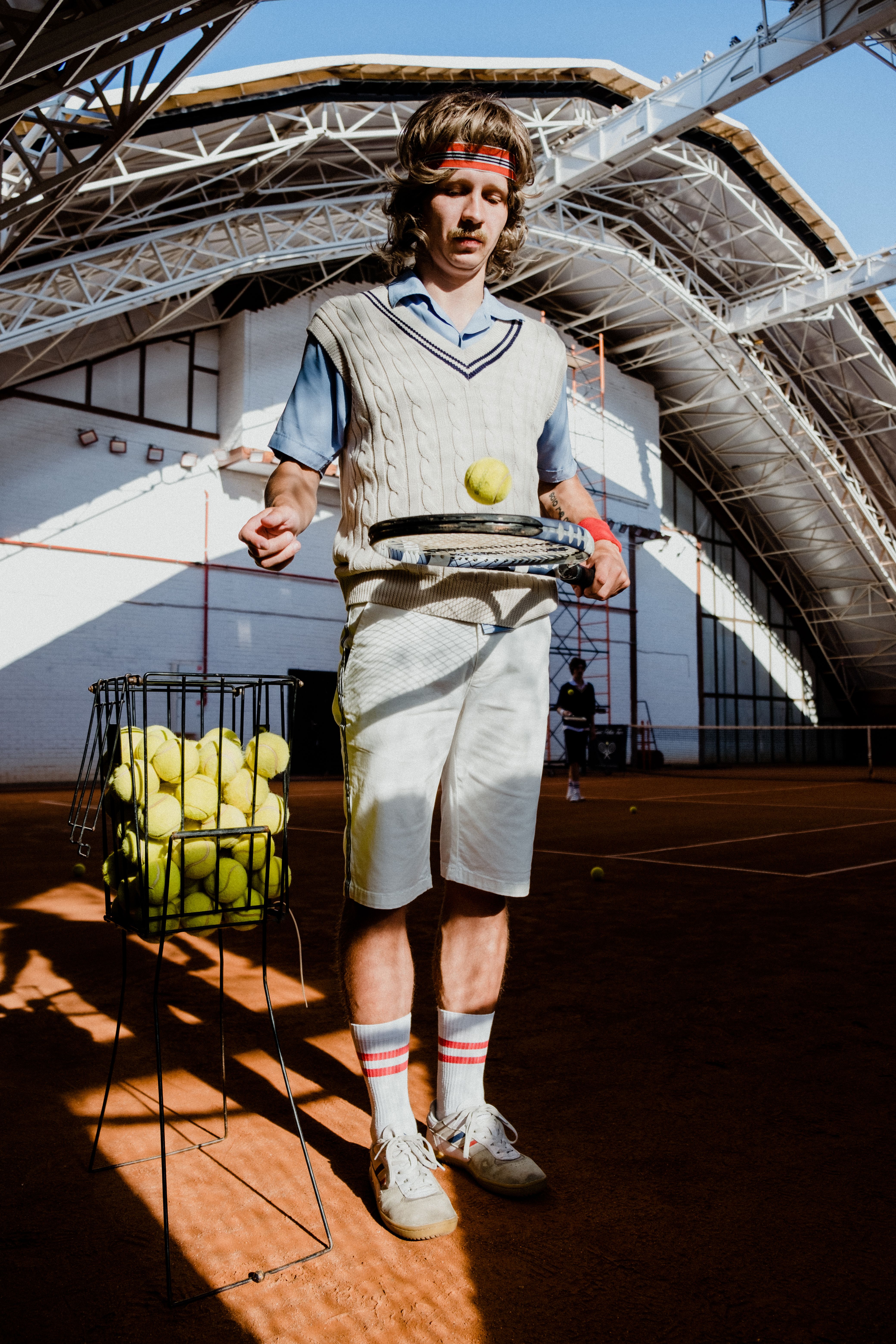 Jugador de tenis mirando la pista vacía con gradas al fondo
