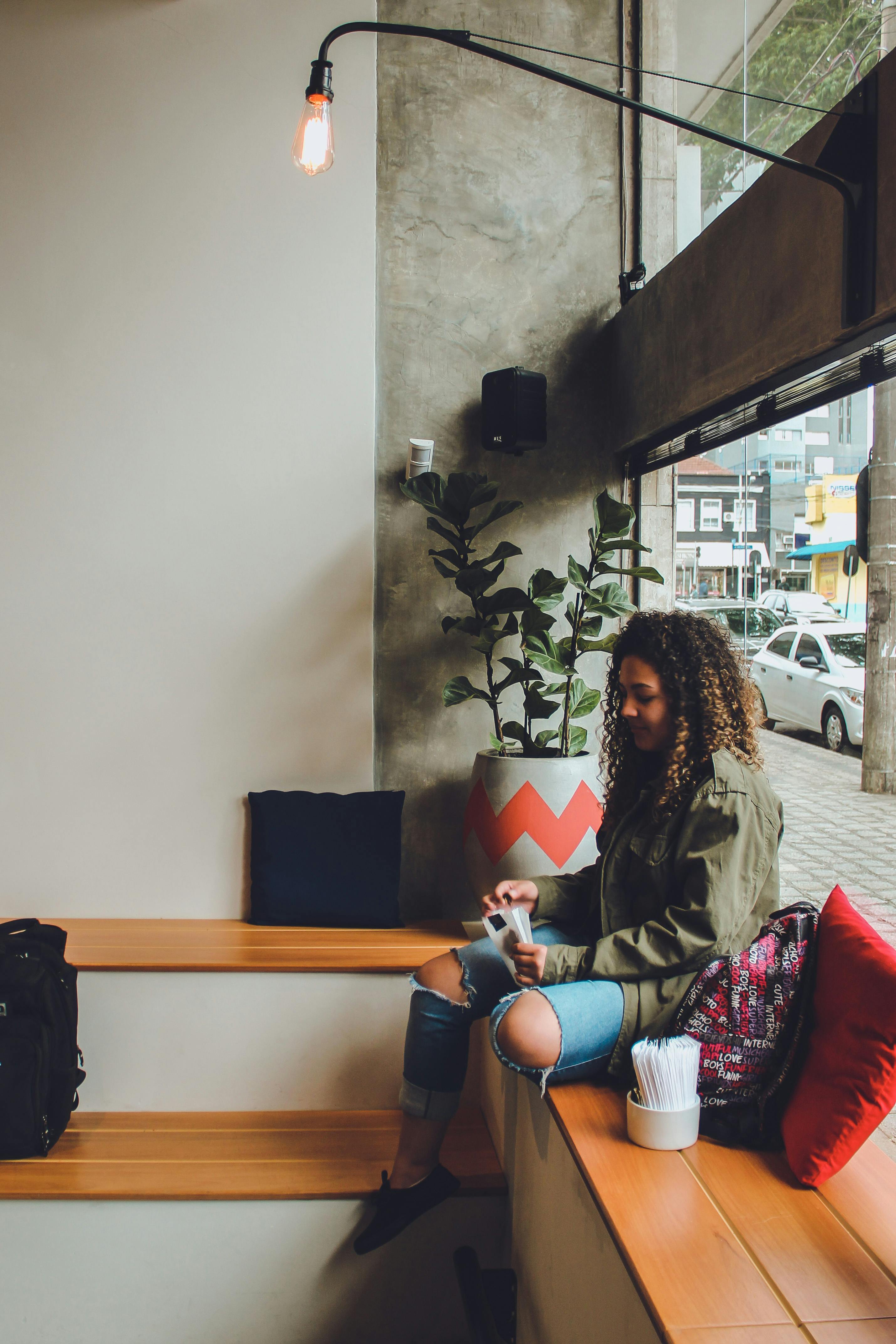 在一家拥有现代内饰和日光氛围的时尚咖啡馆里，一名年轻女子正在放松阅读