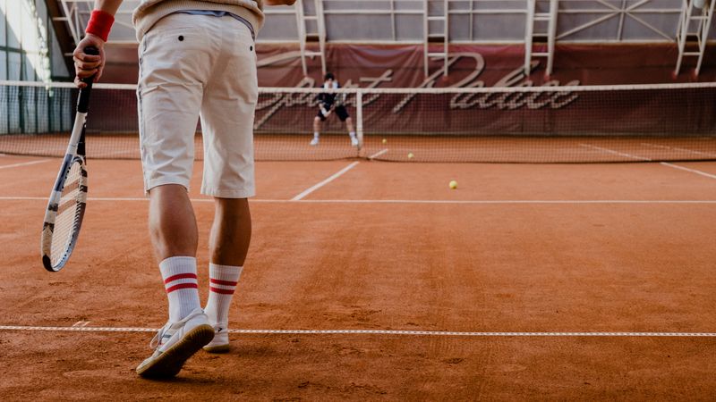 Players competing in a tennis match on an indoor clay court.