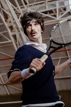 Portrait of a tennis player poised with racquet on an indoor court, showcasing focused athleticism.